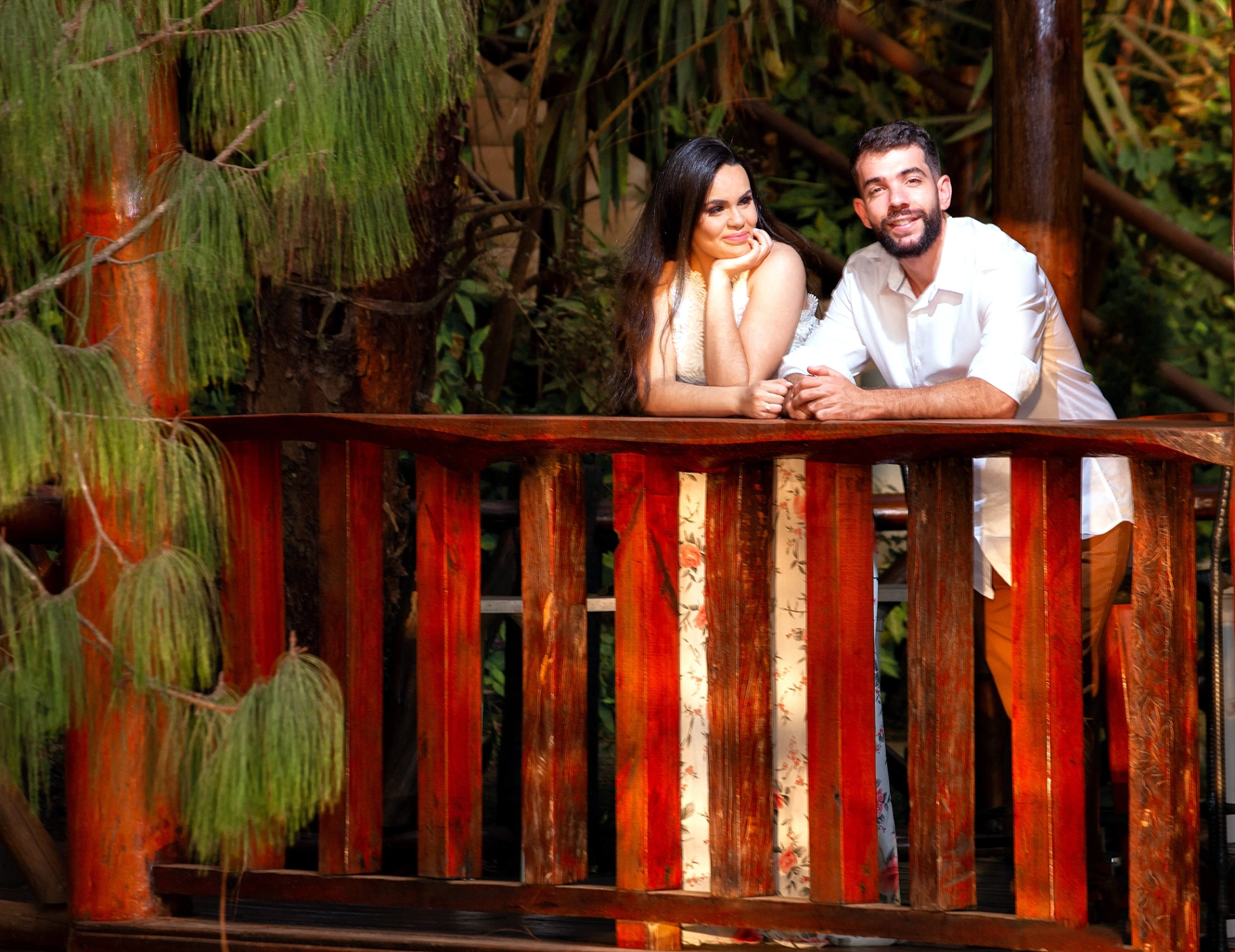 Joaquim e Livia debruçados em ponte de madeira rústica cercada por vegetação